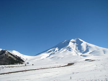 Scenic view of snowcapped mountains against clear blue sky