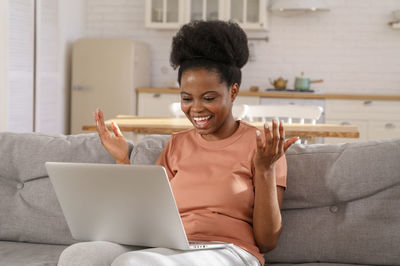 Young man using mobile phone while sitting on sofa