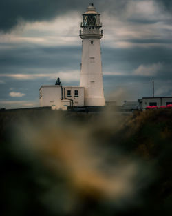 Low angle view of lighthouse by building against sky