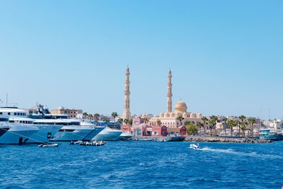 Boats in sea against clear blue sky