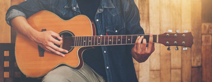 Midsection of man playing guitar