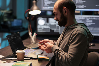 Side view of man using laptop at office
