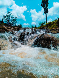 Water flowing through rocks against sky