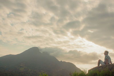 Rear view of people standing on mountain against sky