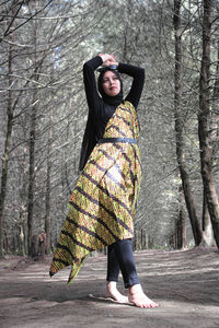 Portrait of woman standing by tree in forest