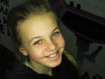 Close-up of girl smiling while standing by wall