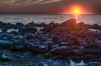 Rocks in sea during sunset