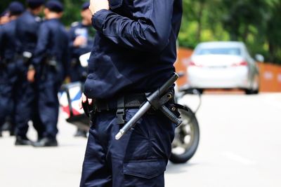 Midsection of police man standing on road