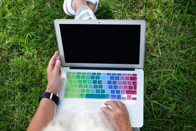 Midsection of person using laptop while sitting on grass