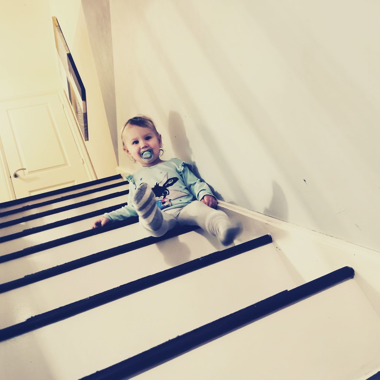 one person, blue, indoors, portrait, adult, emotion, happiness, staircase, smiling, child, looking at camera, men, childhood, lifestyles, architecture, white, full length, casual clothing, person, fun, young adult, striped, clothing, sitting, women