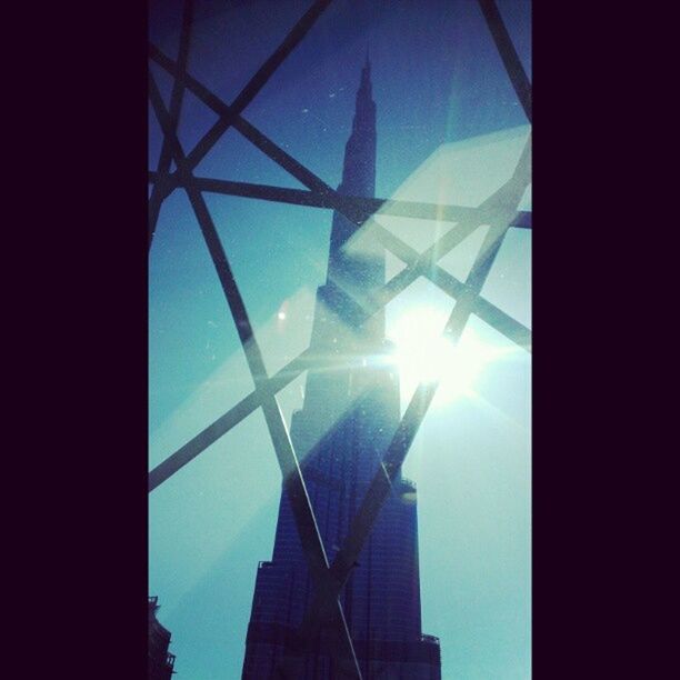 low angle view, sun, architecture, built structure, sunbeam, building exterior, sunlight, sky, modern, lens flare, glass - material, skyscraper, tower, tall - high, city, office building, silhouette, reflection, blue, no people