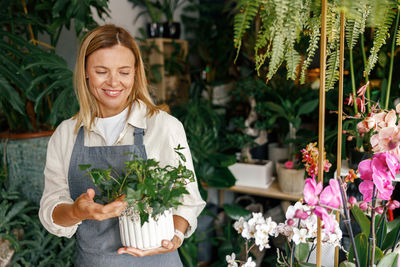 Portrait of smiling young woman standing by plants