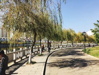 People on footpath in city against clear sky