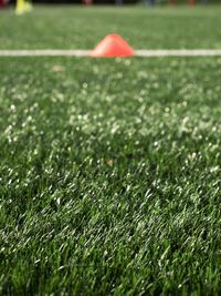 Cones are soccer training equipment on green artificial turf with coach is training kid players