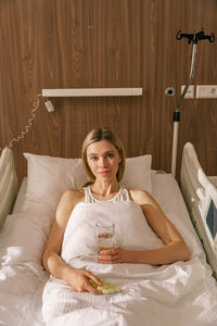 Young woman sitting on bed at home