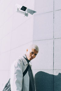 Portrait of young man standing against wall