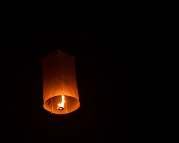 Low angle view of illuminated lantern against black background