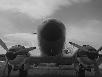 Airplane at airport runway against sky