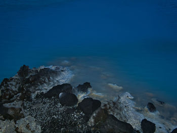 Rocks in sea against blue sky