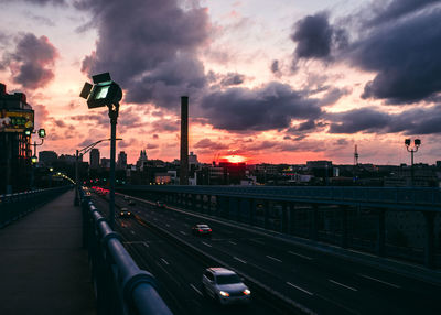 Cars on highway in city against sky during sunset