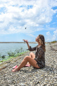 Woman sitting at beach against sky