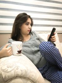 Young woman holding coffee cup on table