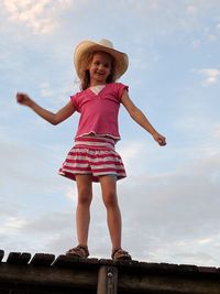 Portrait of girl standing on wooden structure against sky