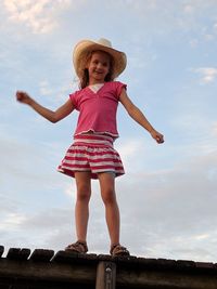 Rear view of a girl standing against cloudy sky