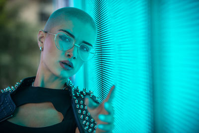 Portrait of young woman with shaved head standing against abstract backgrounds