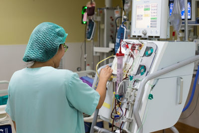 Rear view of woman operating equipment in hospital