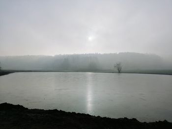 Scenic view of lake against sky during foggy weather