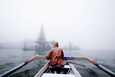 Rear view of man on boat against sky