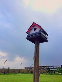 Low angle view of wooden post on field against sky