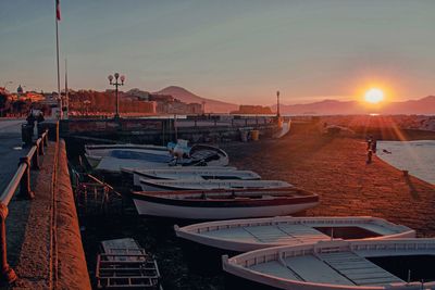 Boats moored at harbor during sunset