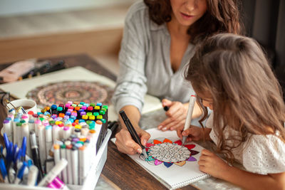 Mother and daughter drawing while sitting at home