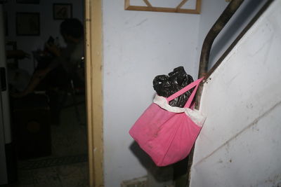 Woman holding pink umbrella standing by door