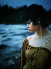 Side view of young woman looking away at lake