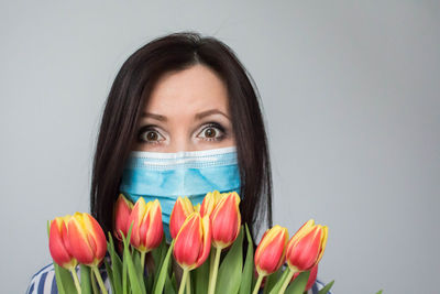 Portrait of woman holding red flower against white background