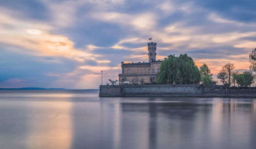 Building by sea against sky during sunset