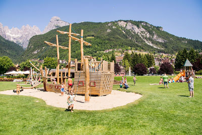 People on field by mountains against sky