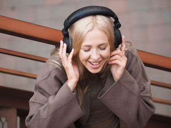 Cheerful woman listening music on headphones