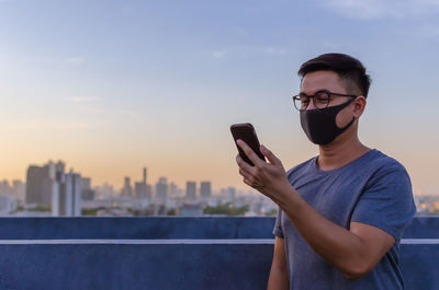 Asian man wearing face mask to protect from virus and make a video call with smartphone.