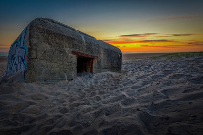 Old ruin on beach against sky during sunset