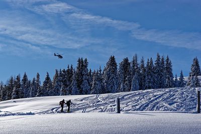 People skiing on snow covered mountain against sky