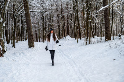 Young woman walking in the snowy winter day outdoor, winter forest landscape background