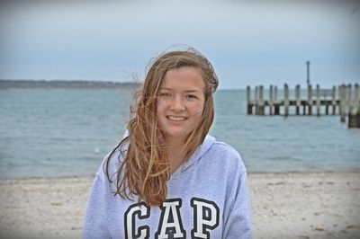 Portrait of smiling woman standing at beach against sky