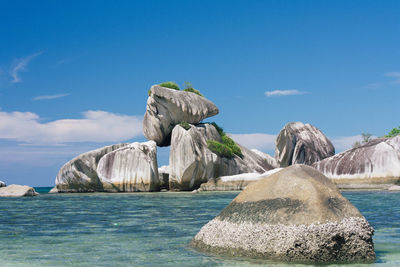 Rocks in sea against blue sky