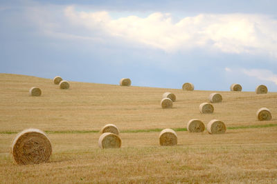 Hay bales on field against sky