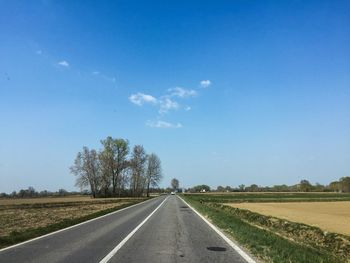 Surface level of road amidst field against sky