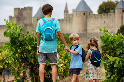 Rear view of siblings standing against trees